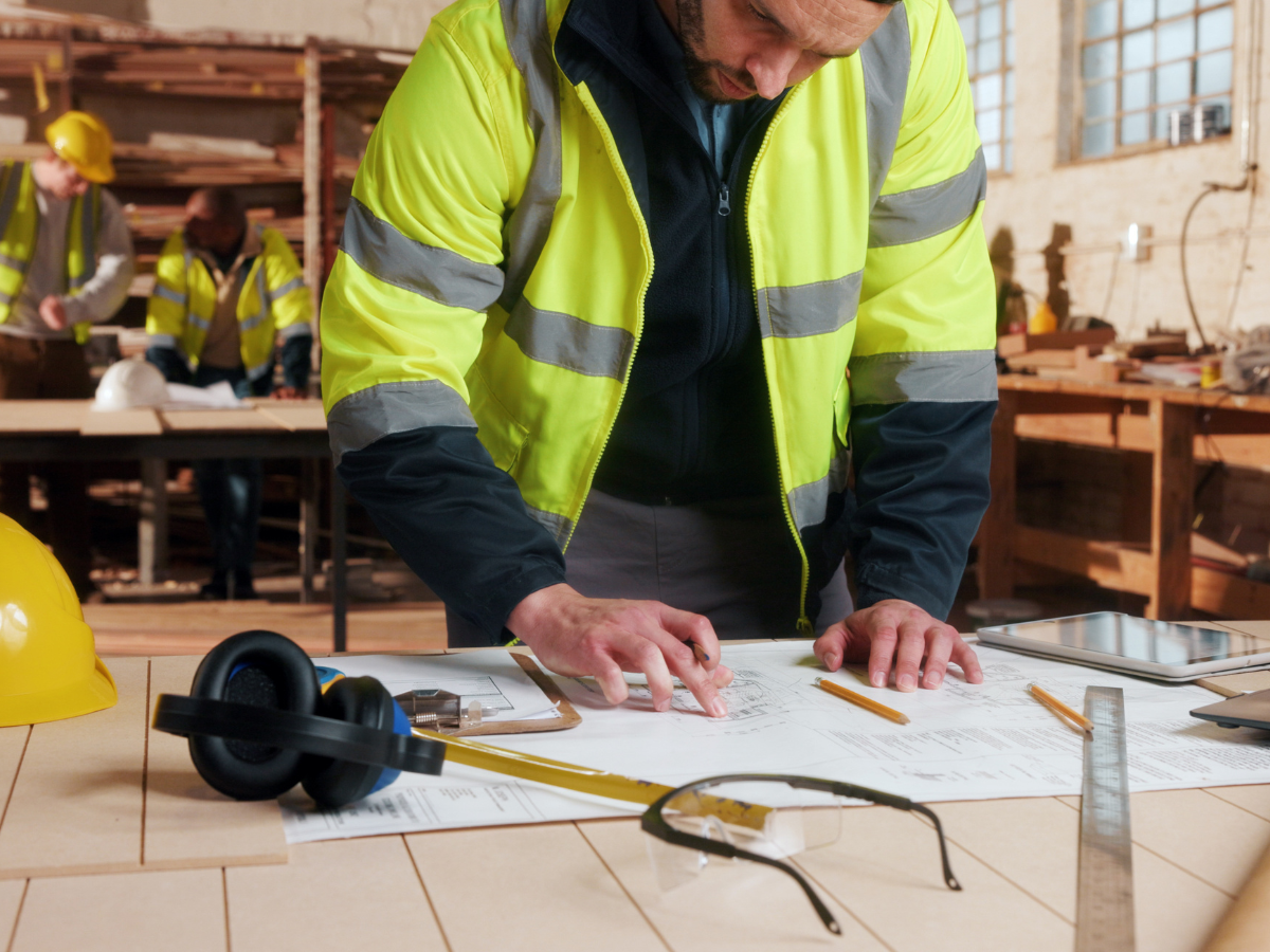 Mitarbeiter im Innenausbau prüft technische Pläne in einer Werkstatt