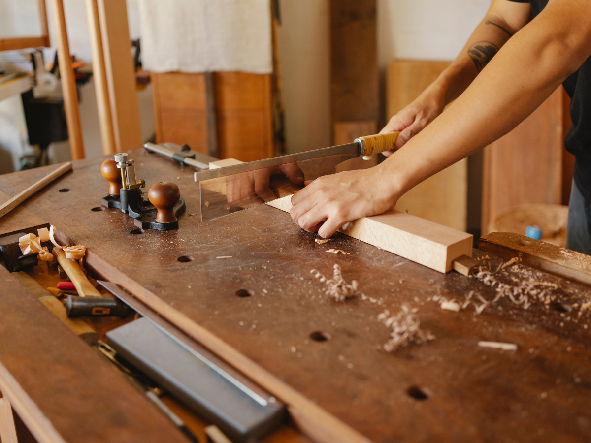 Handwerker sägt ein Holzstück an einer Werkbank in einer Schreinerei