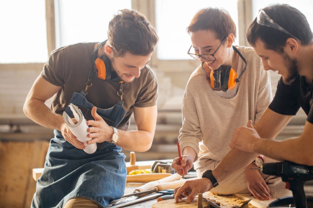 Unterweisung Arbeitssicherheit – Beschäftigte besprechen Arbeitsabläufe und Sicherheitsmaßnahmen in einer Werkstatt